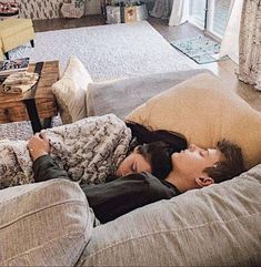 two people laying on a couch in a living room