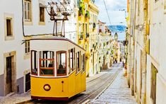 a yellow trolley car traveling down a street next to tall buildings on the other side