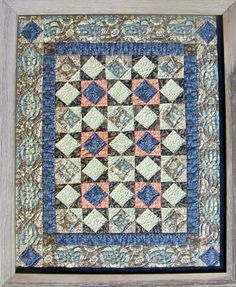 an old quilt hanging in a wooden frame