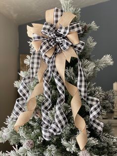 a christmas tree decorated with black and white plaid ribbon, pine cones and twine bows