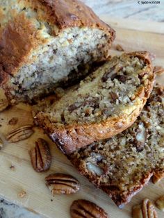 sliced loaf of banana nut bread sitting on top of a cutting board next to pecans