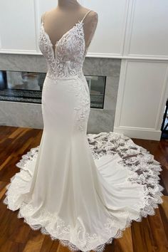 a wedding dress on display in front of a fireplace