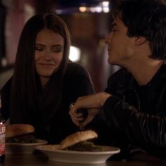 a man and woman sitting at a table eating food