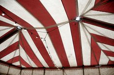 a large red and white tent with string lights hanging from it's ceiling area