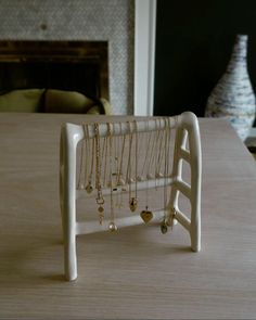 a white jewelry rack with necklaces hanging from it's sides on a table