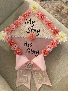 a pink graduation cap with flowers on it and the words my story is glory written in cursive writing