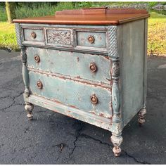 an old dresser is painted blue and has knobs on the bottom, with wood top