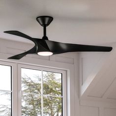 a black ceiling fan sitting in front of a window next to a white wall and windowsill