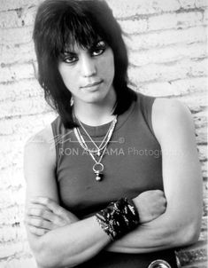 a black and white photo of a woman with her arms crossed in front of a brick wall