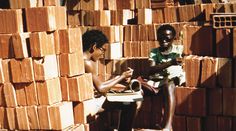 two children are sitting in front of stacks of bricks