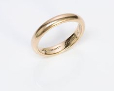 a gold wedding ring on a white background with the word love written in cursive writing