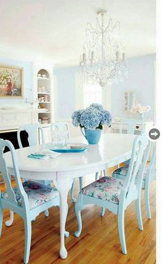 a dining room table and chairs with blue flowers in vases on the centerpiece