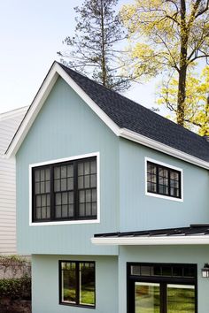 a blue house with two windows and a black roof