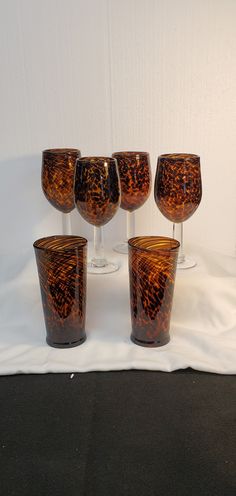 five wine glasses sitting on top of a white cloth covered table next to each other