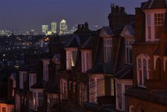 the city skyline is lit up at night, with buildings in the foreground and skyscrapers in the distance