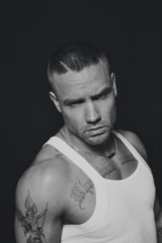 black and white photograph of a man with tattoos on his arm, wearing a tank top