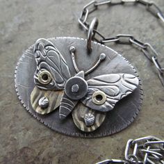 a close up of a butterfly on a metal disc with chains hanging from it's sides