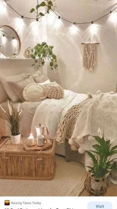 a white bedroom with plants and wicker baskets on the floor, lights strung from the ceiling