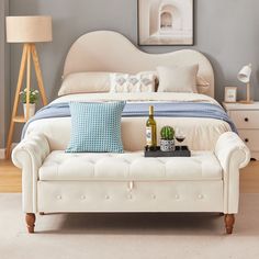 a white bed sitting next to a table with a bottle of wine on top of it