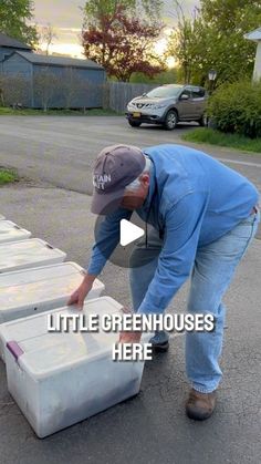 a man bending over to pick up some green house boxes