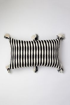 two black and white striped pillows with tassels on the ends, one in front of the other