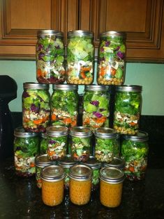 many mason jars filled with different types of salads on a kitchen counter next to a blender