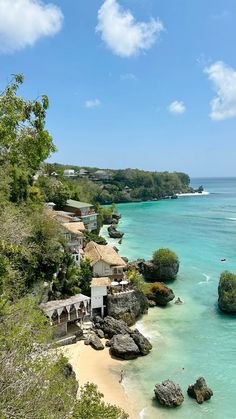 an aerial view of the beach and ocean with houses in the water, surrounded by trees