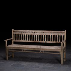 a wooden bench sitting on top of a stone floor in front of a black wall