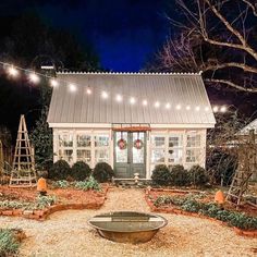 a small white house with christmas lights on the front door and windows in the back yard