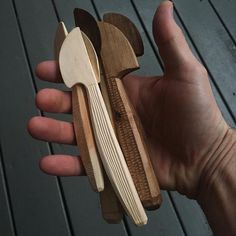 a person holding three wooden spoons in their hand