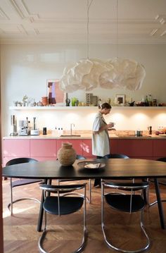 a woman standing in a kitchen next to a table