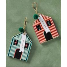 two small tags are hanging from strings on a green surface, one has a house and the other is a cat