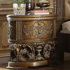 an ornately decorated side table with potted plants on top and books in the middle