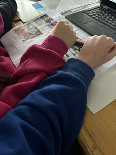 a person sitting at a desk with a laptop and papers in front of them on top of a wooden table