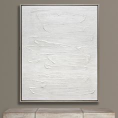 a white painting hanging on the wall above a fireplace