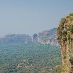 the mountains are covered in green vegetation and rock formations, with trees growing on them