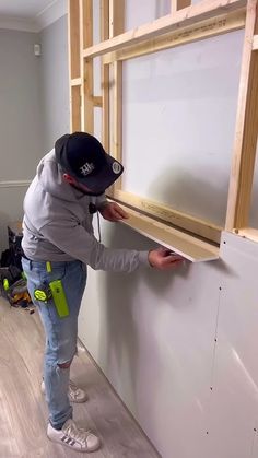 a man in grey jacket and black hat working on window frame