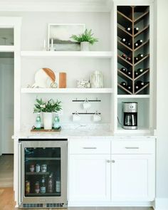 a kitchen with white cabinets and shelves filled with wine bottles, coffee cups, and other items