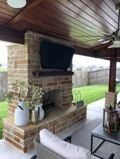 an outdoor living area with furniture and a television on the fireplace in the back yard