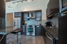 a modern kitchen with stainless steel appliances and granite counter tops, along with dark wood cabinets