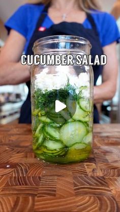 a jar filled with cucumber salad sitting on top of a wooden cutting board