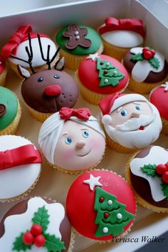 christmas cupcakes in a box with santa clause and reindeer faces on them,