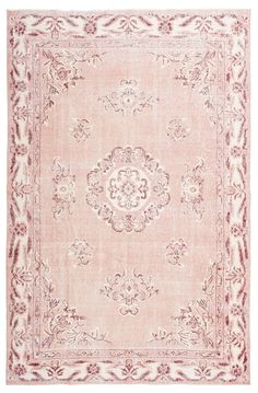 a pink and white rug with an ornate design on the center, in front of a white background