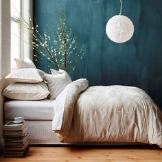 a bedroom with teal walls, white bedding and pillows on the bottom floor