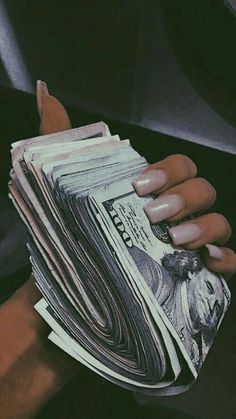 a person holding stacks of money in their left hand with both hands on top of each other