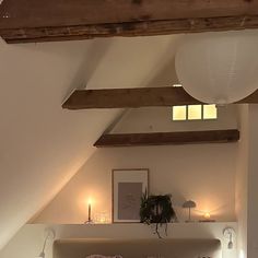 a bed sitting under a window in a bedroom next to a wooden beamed ceiling