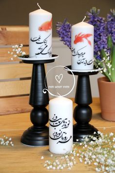 three candles with arabic writing on them sitting on a table next to some lavenders