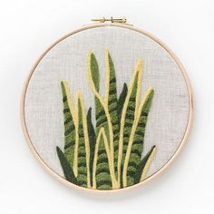 a cross stitch embroidery pattern with green and yellow plants in the center on a white background