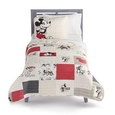 a bed with mickey mouse comforter and pillows