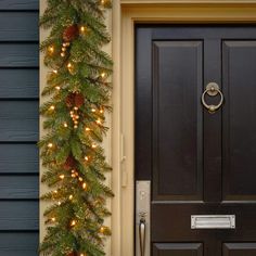 a black door with christmas lights on it and a green garland hanging over the front door